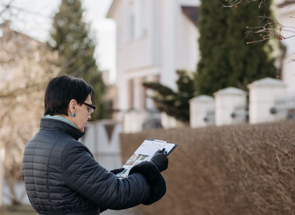 Persona revisando la documentación y el certificado de instalación de aerotermia junto a la vivienda