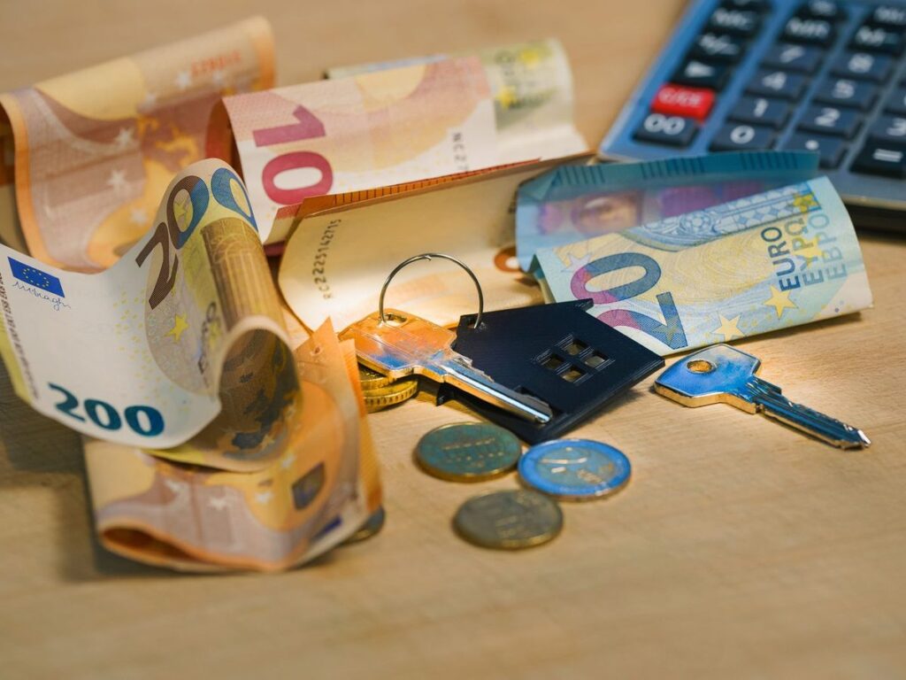Billetes de euro, llavero con forma de casa y calculadora, representando el presupuesto de una instalación de aerotermia