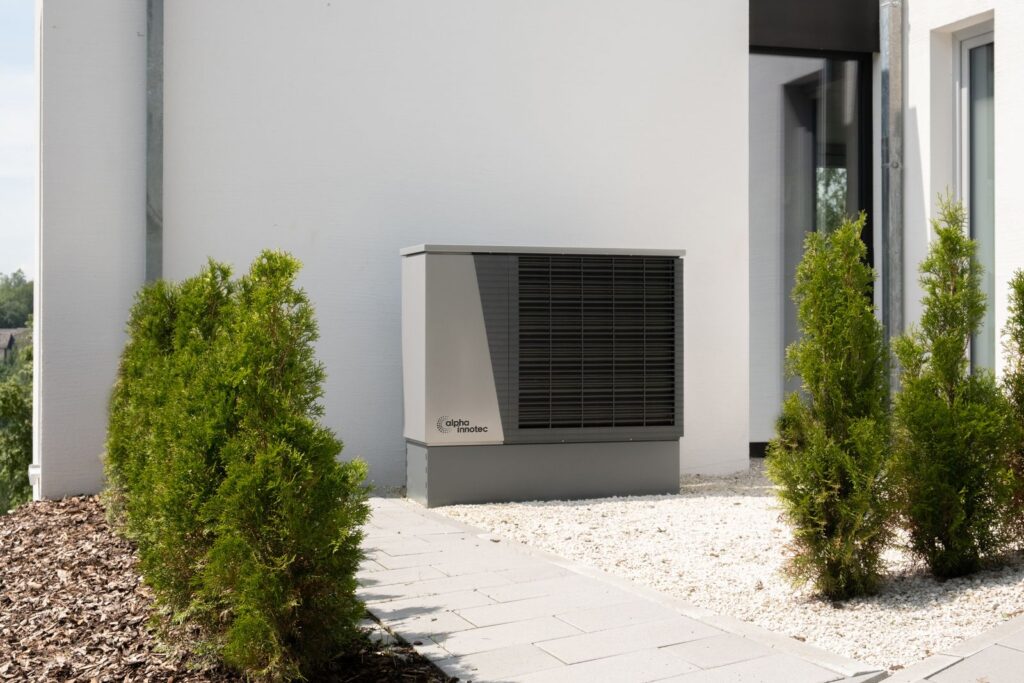 Unidad exterior de aerotermia junto a la fachada de una vivienda unifamiliar moderna de alta eficiencia energética